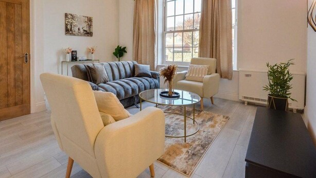 Ein Wohnzimmer mit einer Couch, Sesseln, einem Couchtisch und einer Topfpflanze.