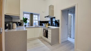Eine moderne Küche mit weißen Schränken, einem eingebauten Backofen und einem Fenster für natürliches Licht.