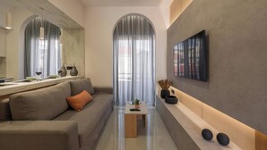A modern living room with a sofa, a coffee table, and a TV mounted on the wall.