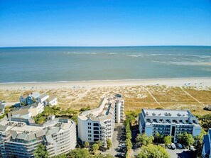 Un hôtel situé sur la côte, composé de plusieurs bâtiments, avec une plage en arrière-plan et un ciel dégagé.