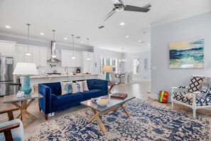 A modern kitchen with white cabinets, a blue sofa, and a dining area with a white table and chairs.