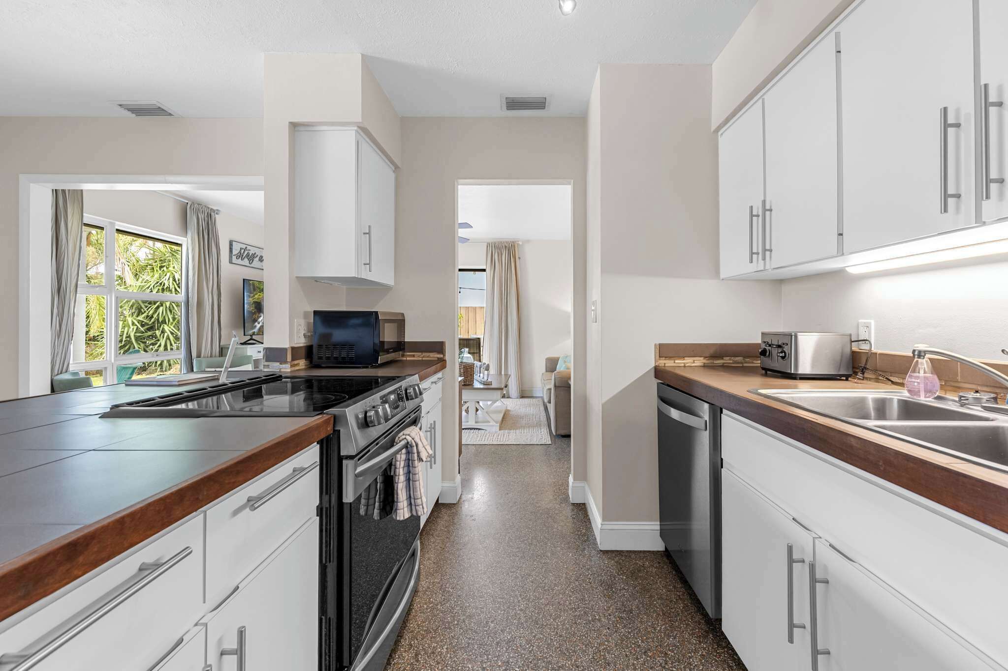 A modern kitchen with white cabinets, a built-in oven, a microwave, and a dishwasher.