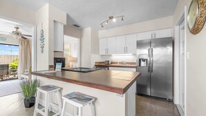 A modern kitchen with a central island, stainless steel appliances, and a view to the outside. - 3BR Cocoa Beach Oasis | 1 Block to Beach (Cocoa Beach)