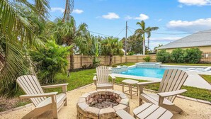 A backyard with a swimming pool, a fire pit, and outdoor furniture. - 3BR Cocoa Beach Oasis | 1 Block to Beach (Cocoa Beach)
