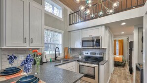 A modern kitchen with white cabinets, a stainless steel stove, and a microwave.