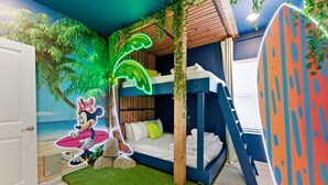 A room with a bunk bed, a mural of a beach scene, and a surfboard decoration.