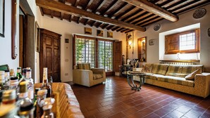 A cozy living room with a wooden ceiling, a sofa, a coffee table, and a bar area with bottles. - Villa Dei Pavoni - Luxury Villa on top of hills in Florence (Toscana)
