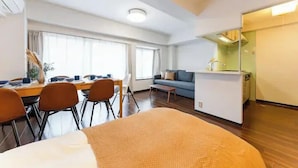 Ein modernes Hotelzimmer mit einem großen Bett, einem Essbereich mit Stühlen und Tisch, einer Couch und einer Küchenzeile.