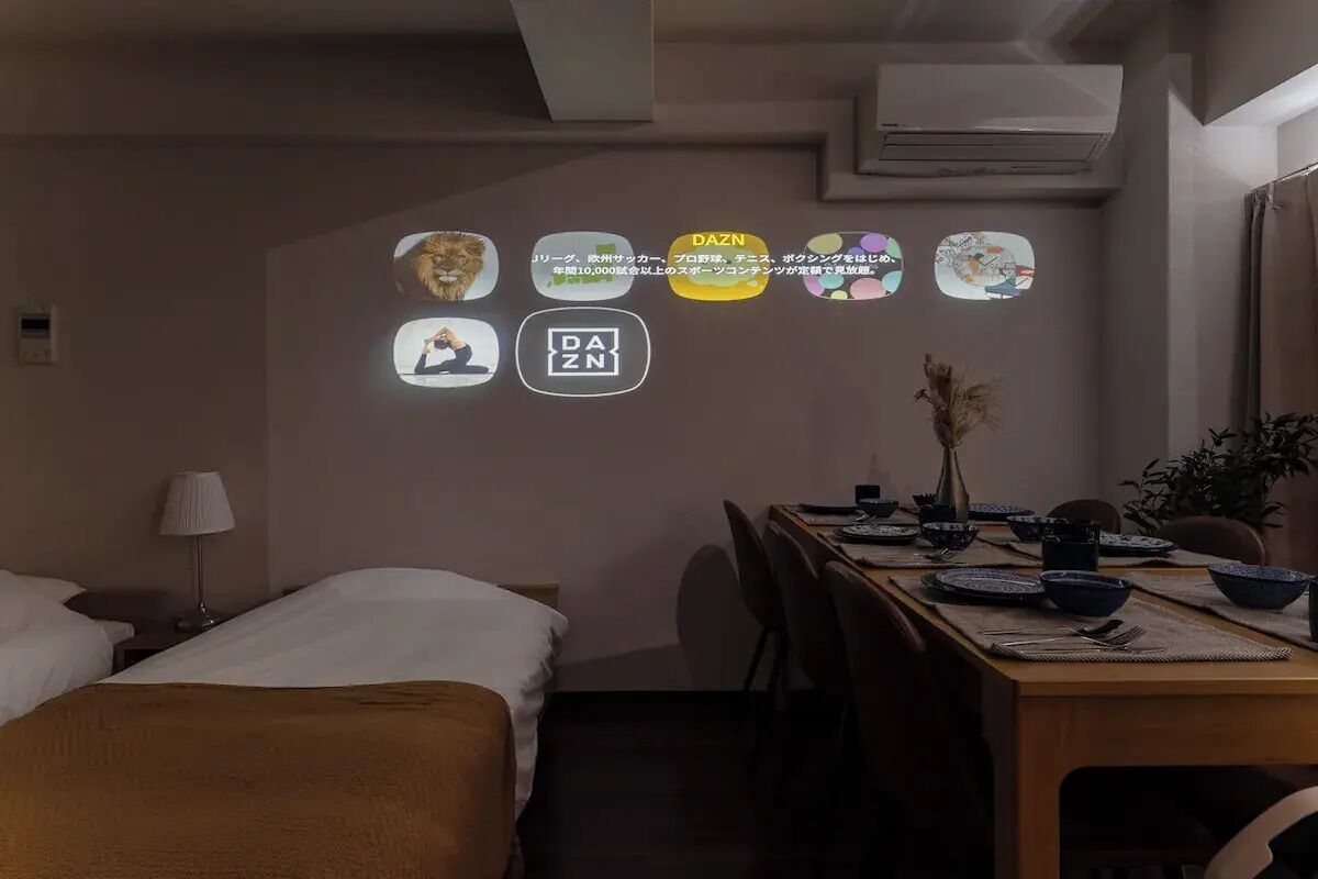 Una habitación de hotel con una cama, un escritorio con lámpara y una mesa de comedor para dos.