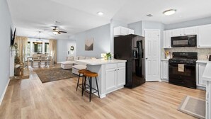 Una cocina moderna con armarios blancos, un refrigerador negro y un microondas.