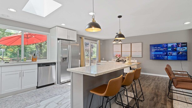 A modern kitchen with a central island, bar stools, and pendant lighting. - Chic Kirkland Home Overlooking Windsor Vista Park (Kirkland)