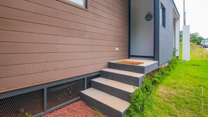 Una casa moderna con revestimiento horizontal, un pequeño porche con escalones y una ventana.