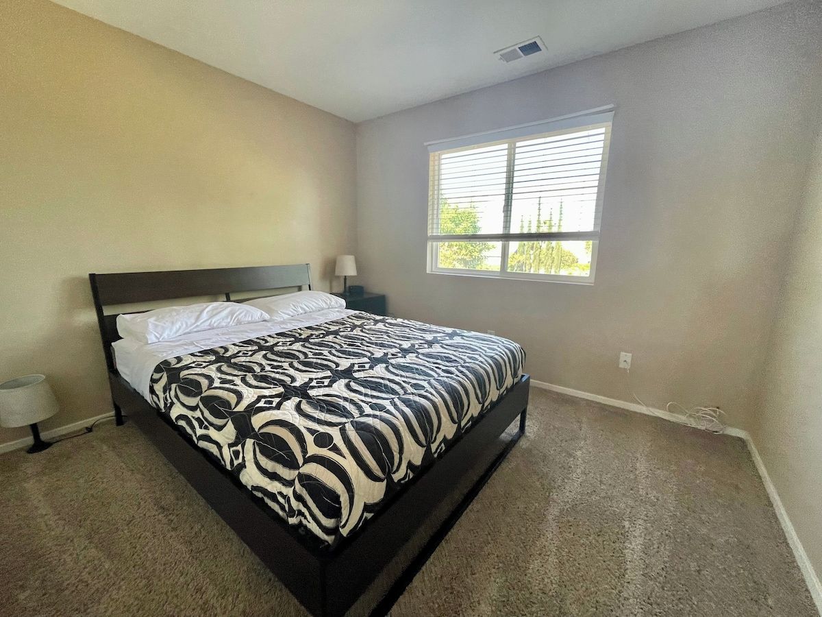 A bedroom with a bed, a window, and a nightstand.