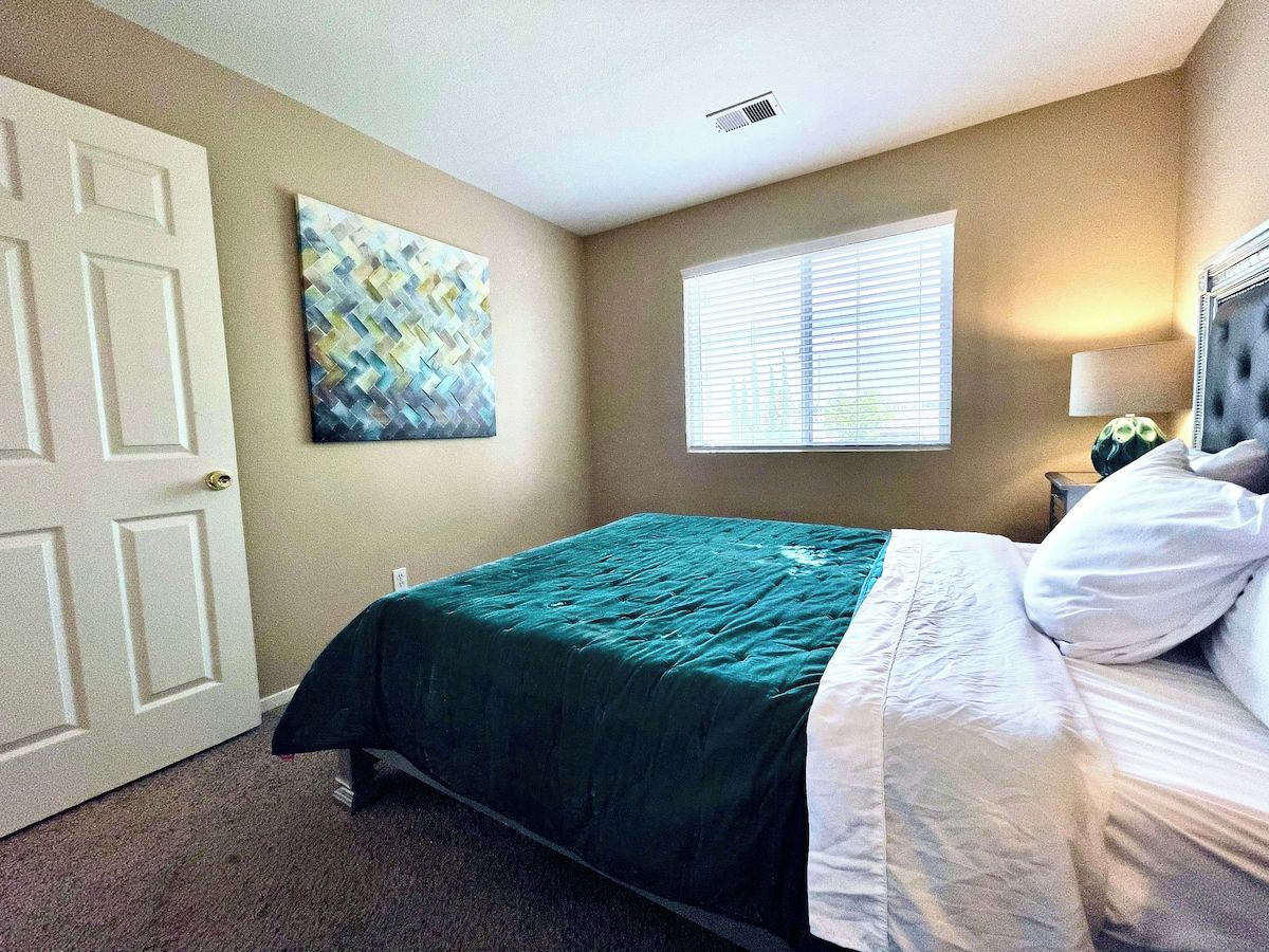 Une chambre à coucher avec un lit, une porte, une fenêtre et une œuvre d’art accrochée au mur.