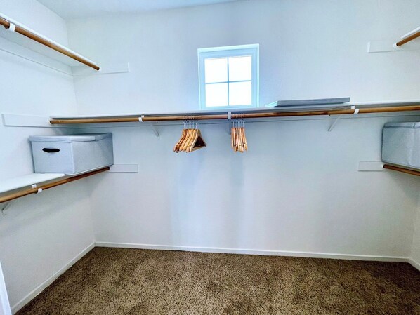 Une pièce avec une fenêtre, deux étagères en bois et une boîte de rangement.