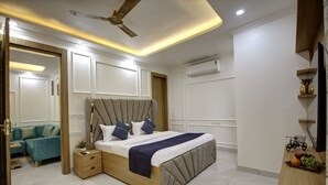 A modern bedroom with a bed, nightstands, a ceiling fan, and a small table with fruits. - MIYABI HOTEL (Gurugram)
