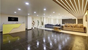 A modern reception area with a reception desk, sofas, and a polished floor. - MIYABI HOTEL (Gurugram)