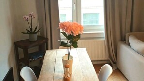 Une table à manger ornée d’un vase de fleurs, d’une plante en pot et d’une lampe.