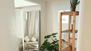 Un salon moderne avec un plancher en bois, un canapé, une table basse et une étagère en bois agrémentée de plantes.