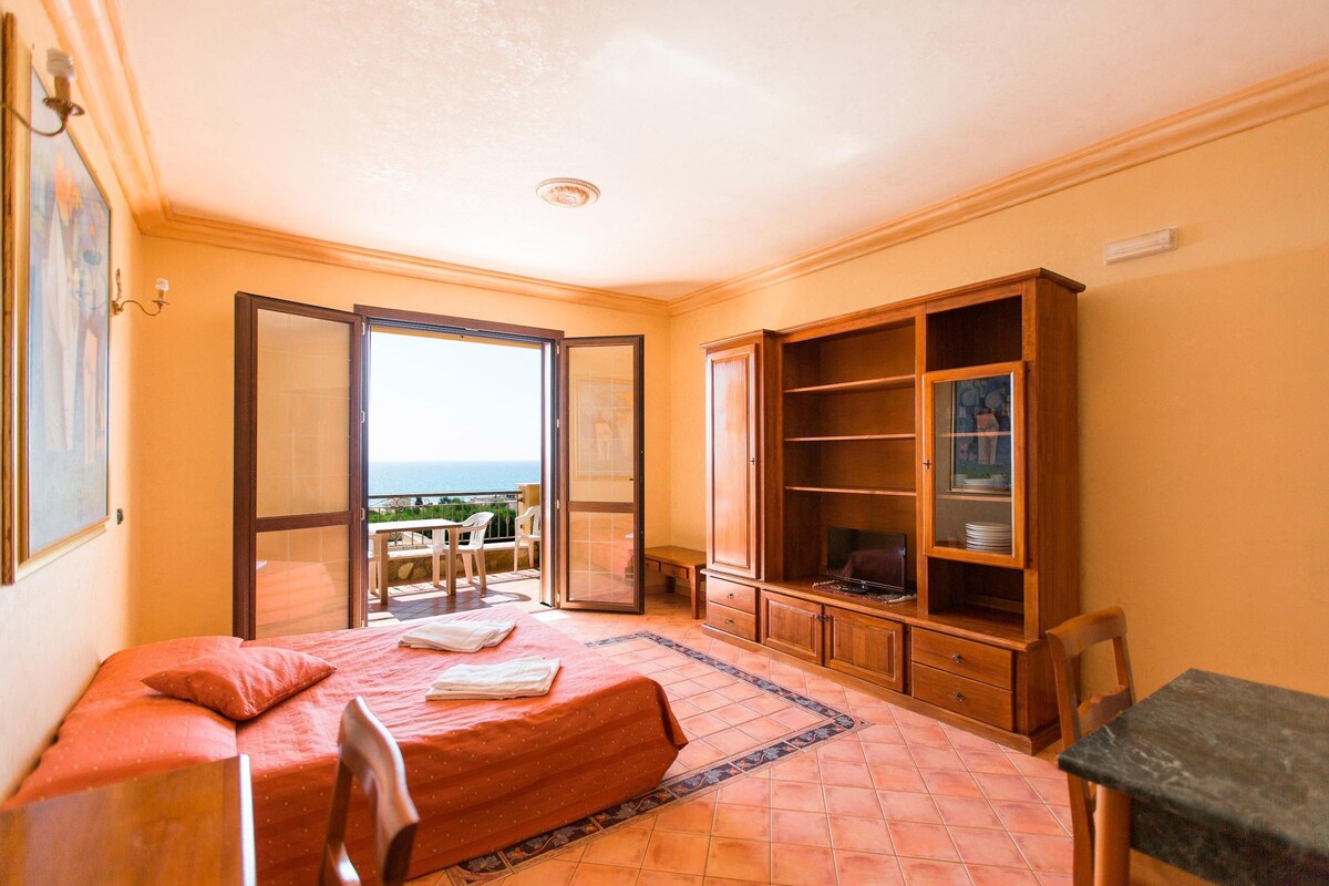 Un dormitorio con cama, un armario de madera y un balcón con vistas.