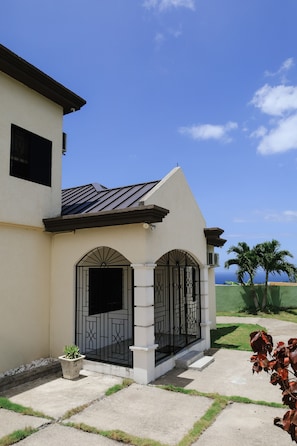 A house with a white exterior, a black metal gate, and a small potted plant.