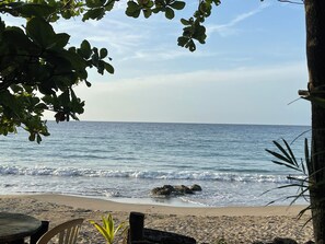 A beach with a wooden table and chairs, a rocky shoreline, and a clear view of the ocean. - Charming apartment in fabulous St. Mary Parish. 15 minutes away from Ocho Rios  (St. Mary Parish)