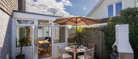 Een terras met een tafel, stoelen, een barbecue en een bloempot.