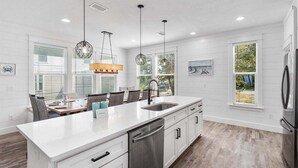 Una cocina moderna con una isla grande, armarios blancos e iluminación colgante.