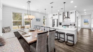Una cocina moderna con armarios blancos, una isla central y taburetes de bar.