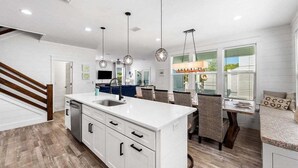 Una cocina moderna con armarios blancos, una isla central con lavamanos e iluminación colgante.