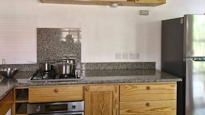 Een keuken met granieten aanrechtbladen, houten kastjes, een roestvrijstalen koelkast en een ingebouwde oven.
