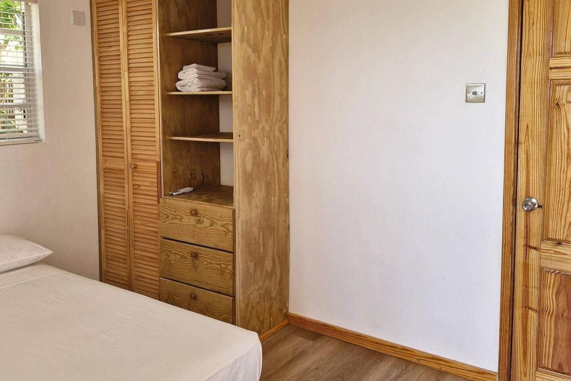 A bedroom with a wooden wardrobe, a bed, and a door.