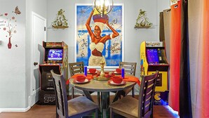Een eethoek met arcade spelletjes, een tafel gedekt voor vier personen en een muurschildering.