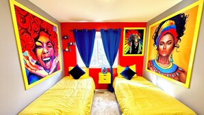 Een kamer met twee bedden, rode wanden en kleurrijke kunstwerken.