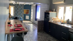 Una cocina moderna con comedor, que presenta una mesa de madera preparada para dos personas, un horno empotrado y una ventana con vistas.