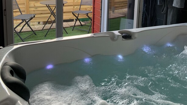Jacuzzi con vista a una cerca de madera y muebles de jardín al aire libre.