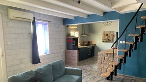 Una sala de estar moderna con un sofá, una mesita y una escalera que da a una zona de cocina.