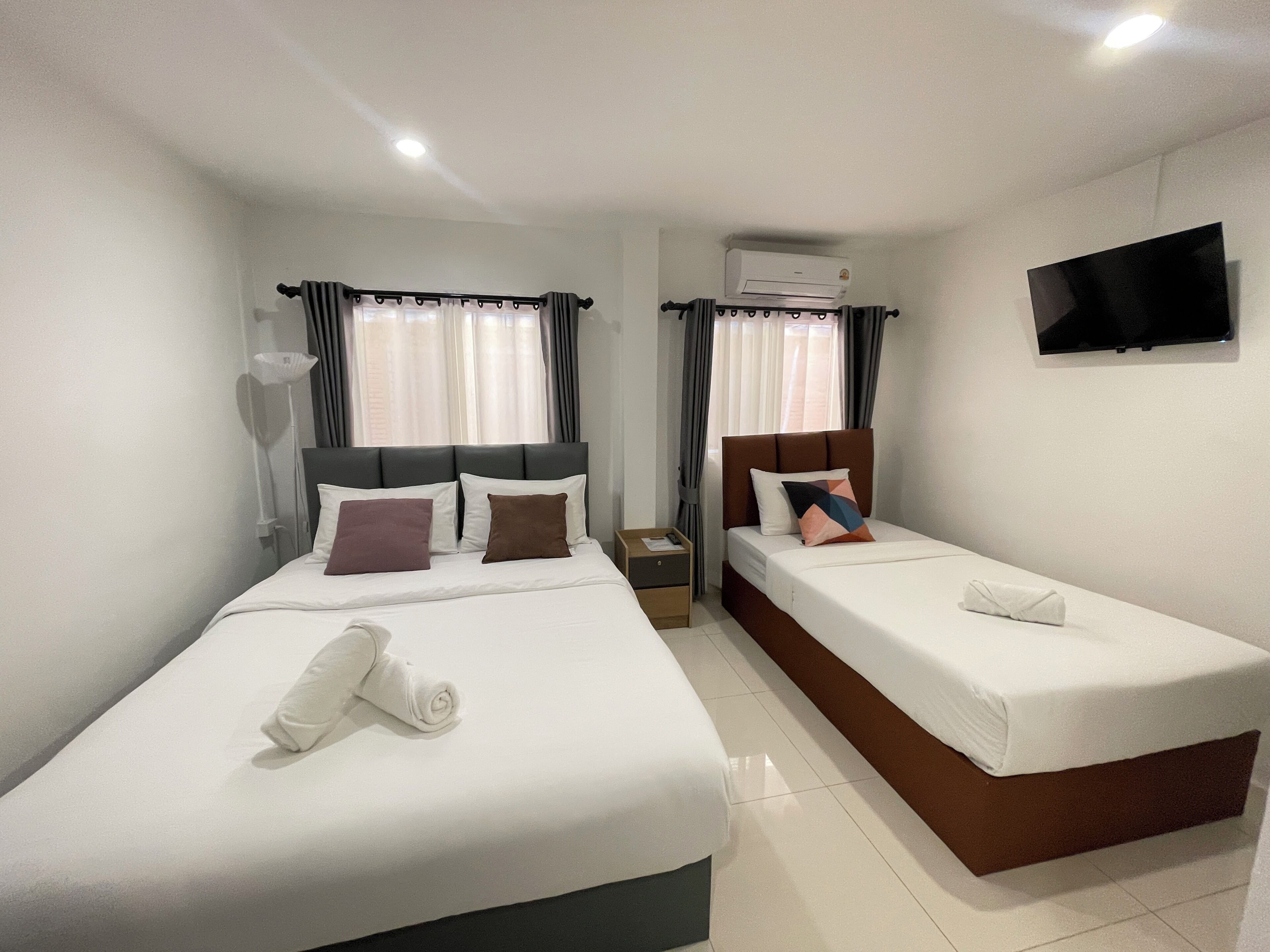A hotel room with two beds, a flat-screen TV, and an air conditioning unit.