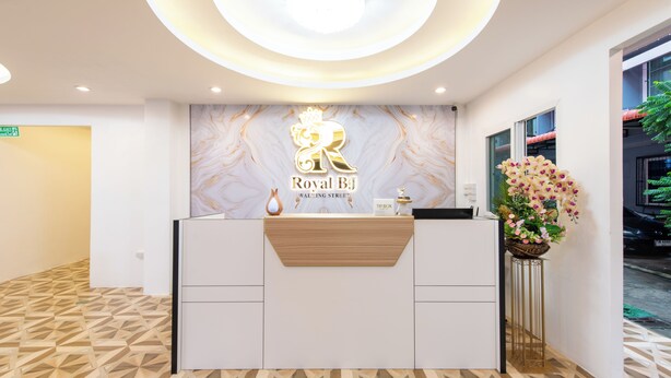 A reception desk with a marble wall and a logo that reads "Royal BJ." - Royal BJ Hotel (Pattaya)