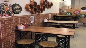 A restaurant interior with brick walls, wooden tables, hexagonal shelves, and various beer bottle labels. - Royal BJ Hotel (Pattaya)