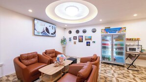 A room with a sofa set, a coffee table, a wall-mounted TV, a refrigerator, and a microwave. - Royal BJ Hotel (Pattaya)
