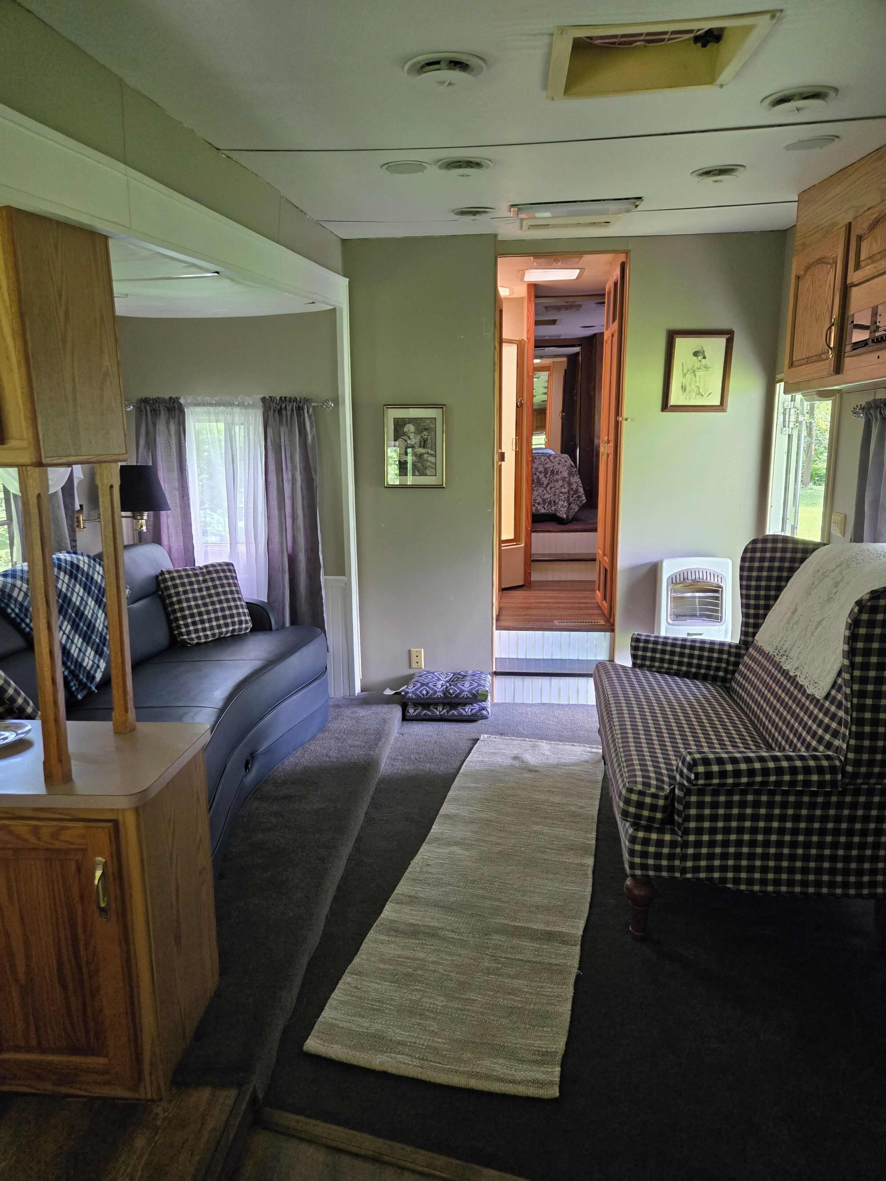 Un interior de caravana acogedor con sofá, una mesita y una ventana con cortinas.