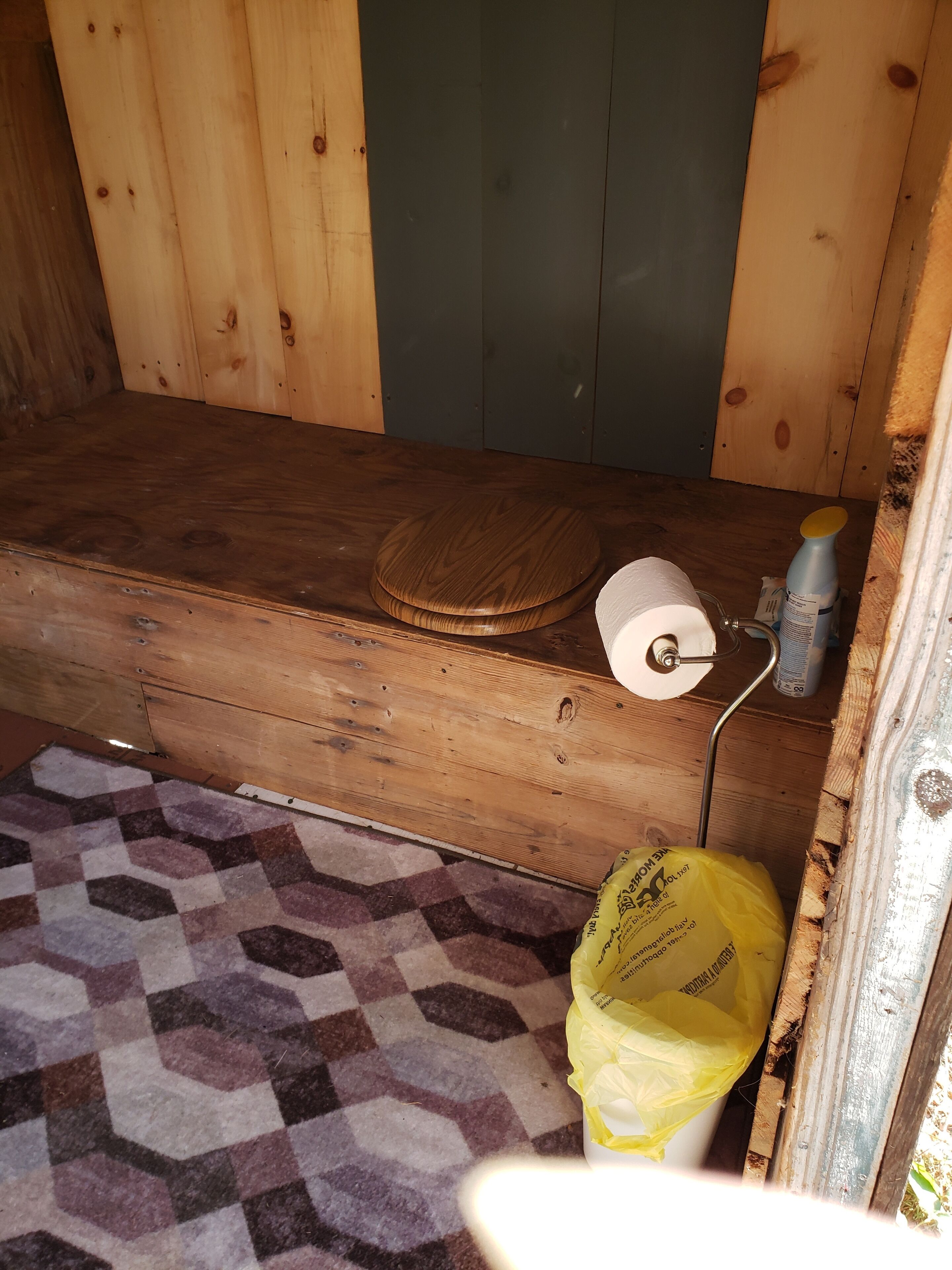 Une petite pièce en bois avec un lit simple, des toilettes et un tapis.