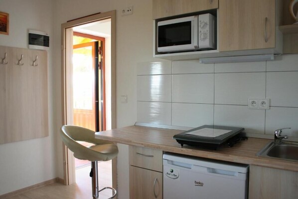 A kitchen with a microwave, a dishwasher, and a chair. - PENZION POD PALAVU (Šakvice)