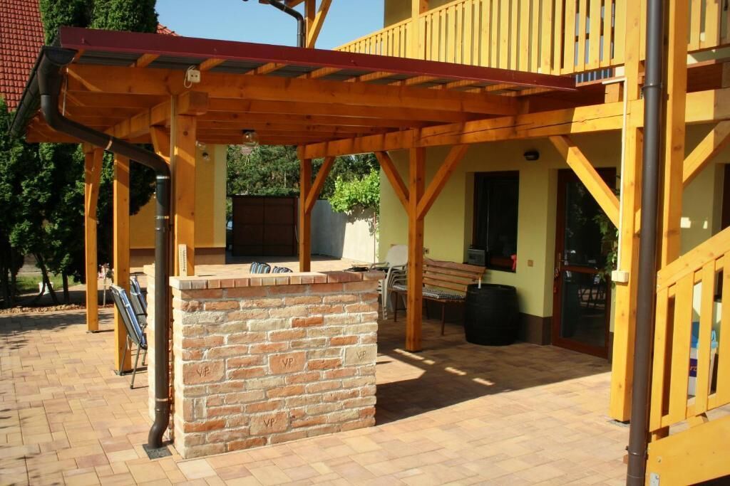 Un espacio de patio cubierto con chimenea de ladrillo, terraza de madera y asientos exteriores.