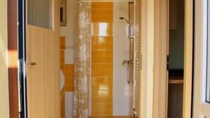 A hallway with a shower area, a door leading to a room, and a tiled floor.