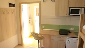 A small kitchen with a microwave, a dishwasher, and a green-tiled backsplash.