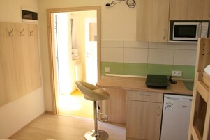 A small kitchen with a microwave, a dishwasher, and a green-tiled backsplash.