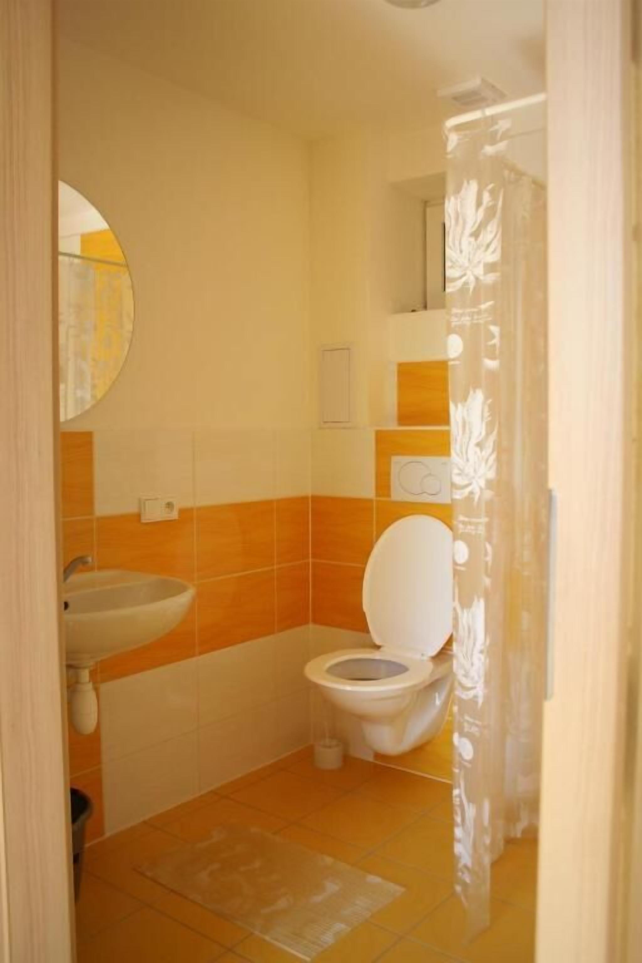 A bathroom with a toilet, sink, and mirror.
