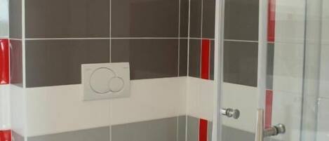 A small bathroom with a toilet, a shower, and a glass door.